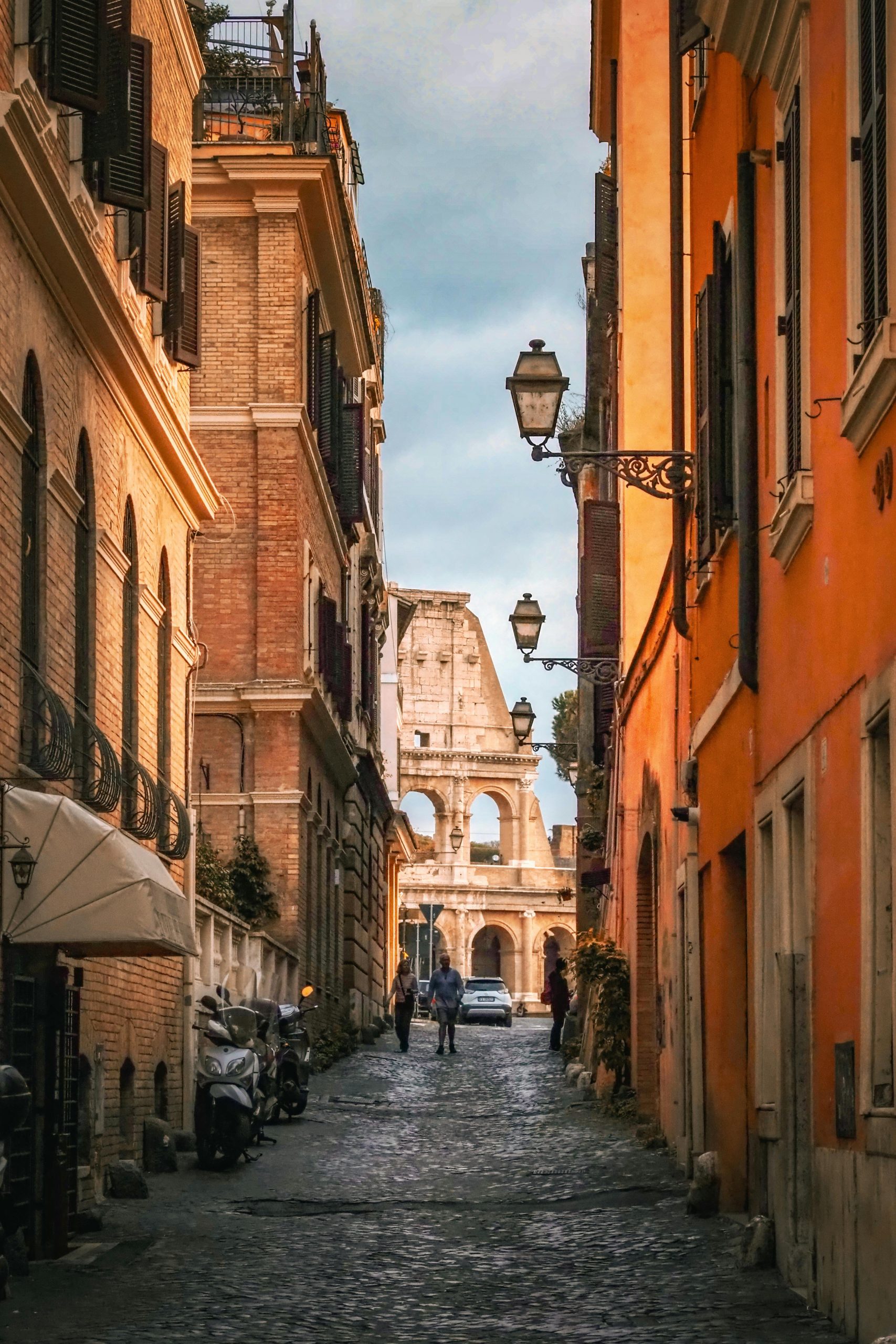 Gaze down a quaint Roman street with the iconic Colosseum framed in the distance.